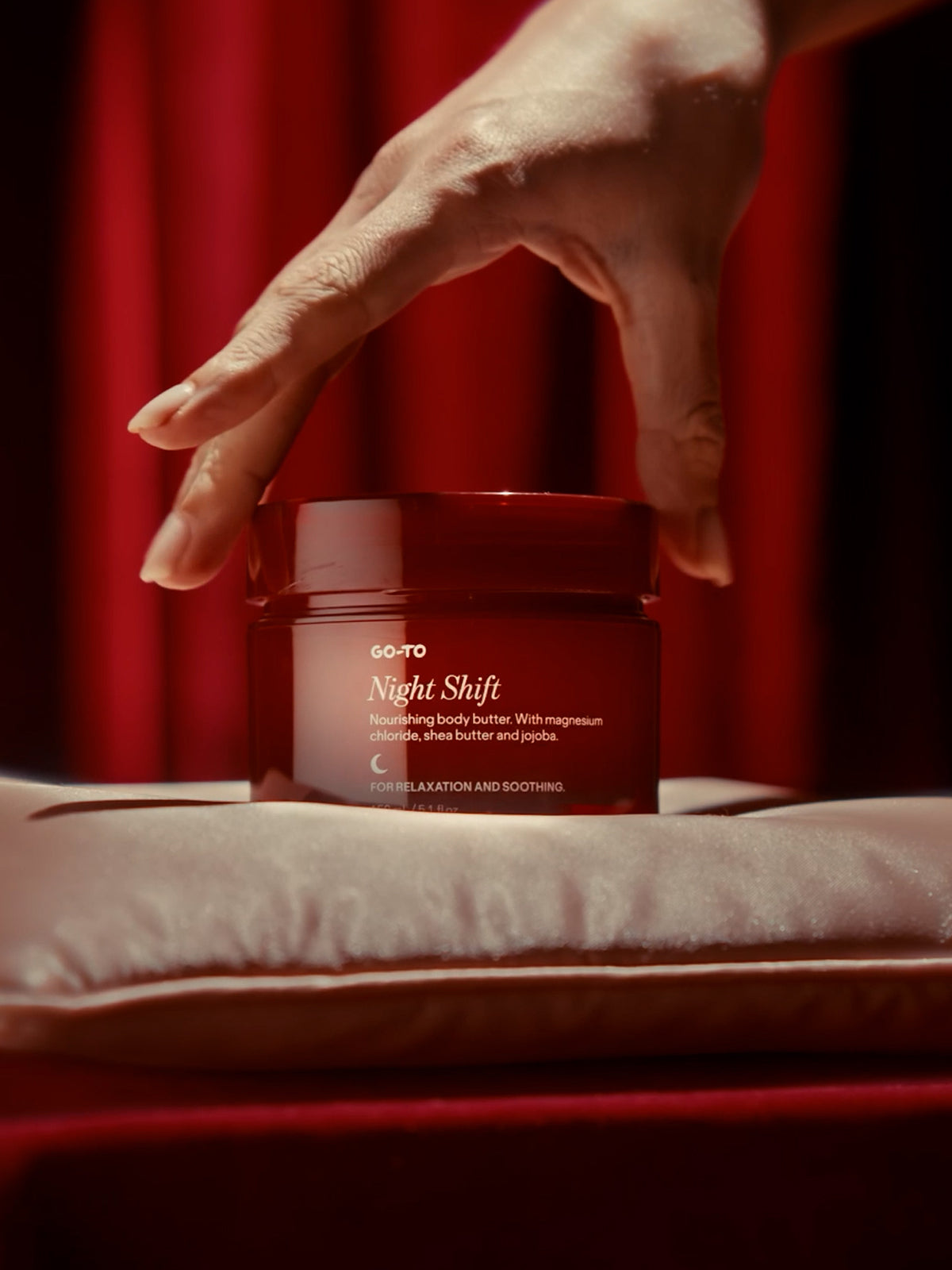 Red jar of 'Night Shift' body butter on a red background